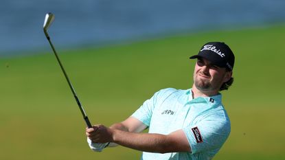 Cameron Adam hits an iron shot and watches it