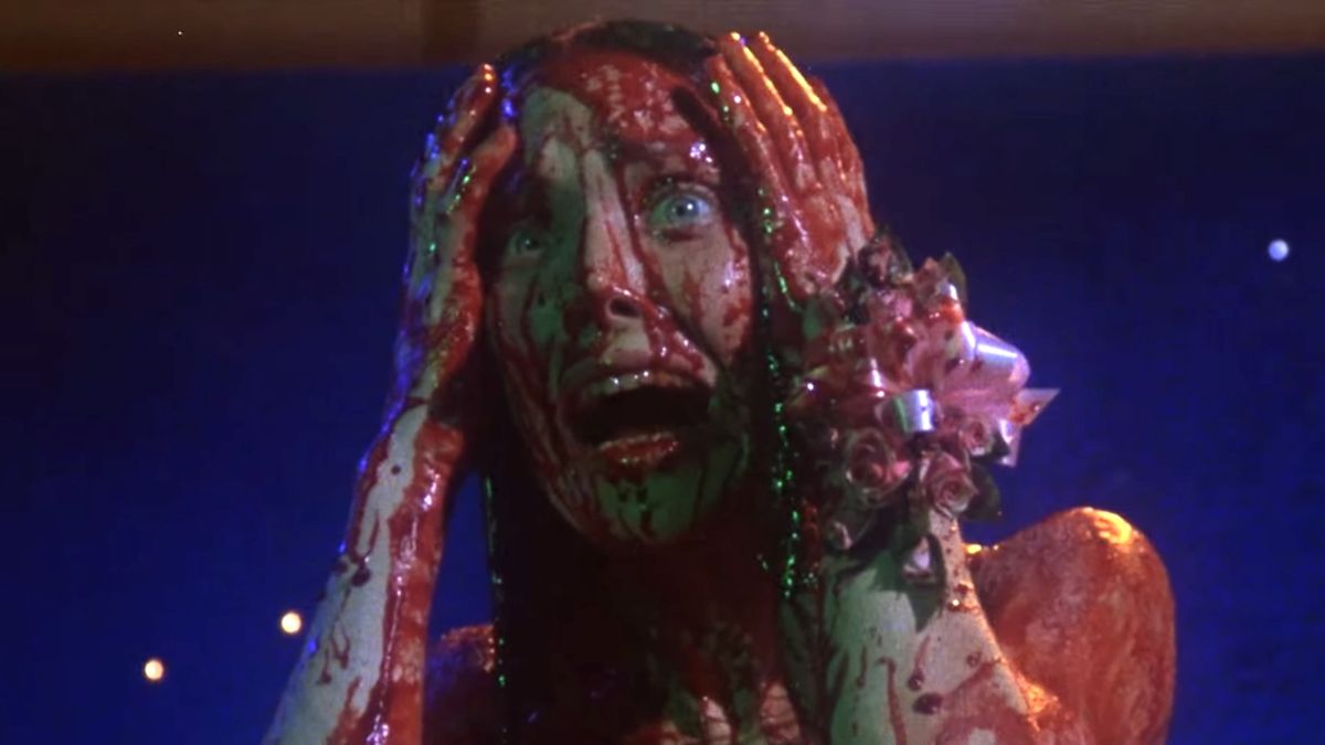 Sissy Spacek holds her head in shock while covered in blood in Carrie.