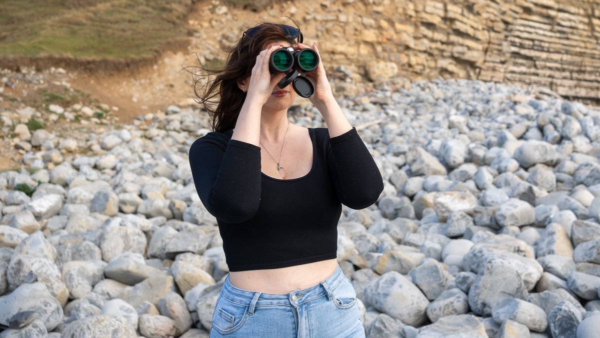 woman using the Celestron TrailSeeker ED 10x42 on a rocky beach