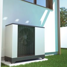 A white heatpump outside a white wall