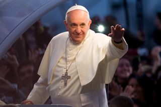 Pope Francis wears white robes and waves at the crowd