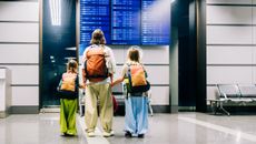 A mother and her two kids check the flight schedule at the airport.