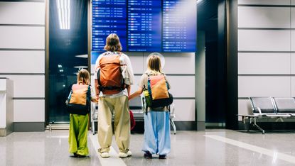 A mother and her two kids check the flight schedule at the airport.