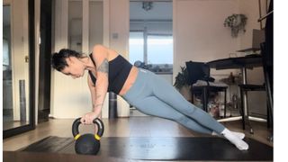 Writer Sam Hopes performing a plank rotation using a kettlebell on the best yoga mats