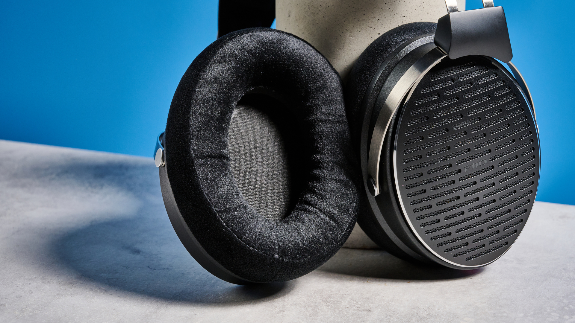 the FiiO JT3 headphones in black and silver shown against a blue tom's guide background