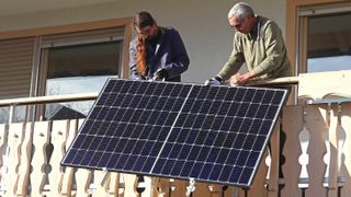 Two people installing solar panel on balcony