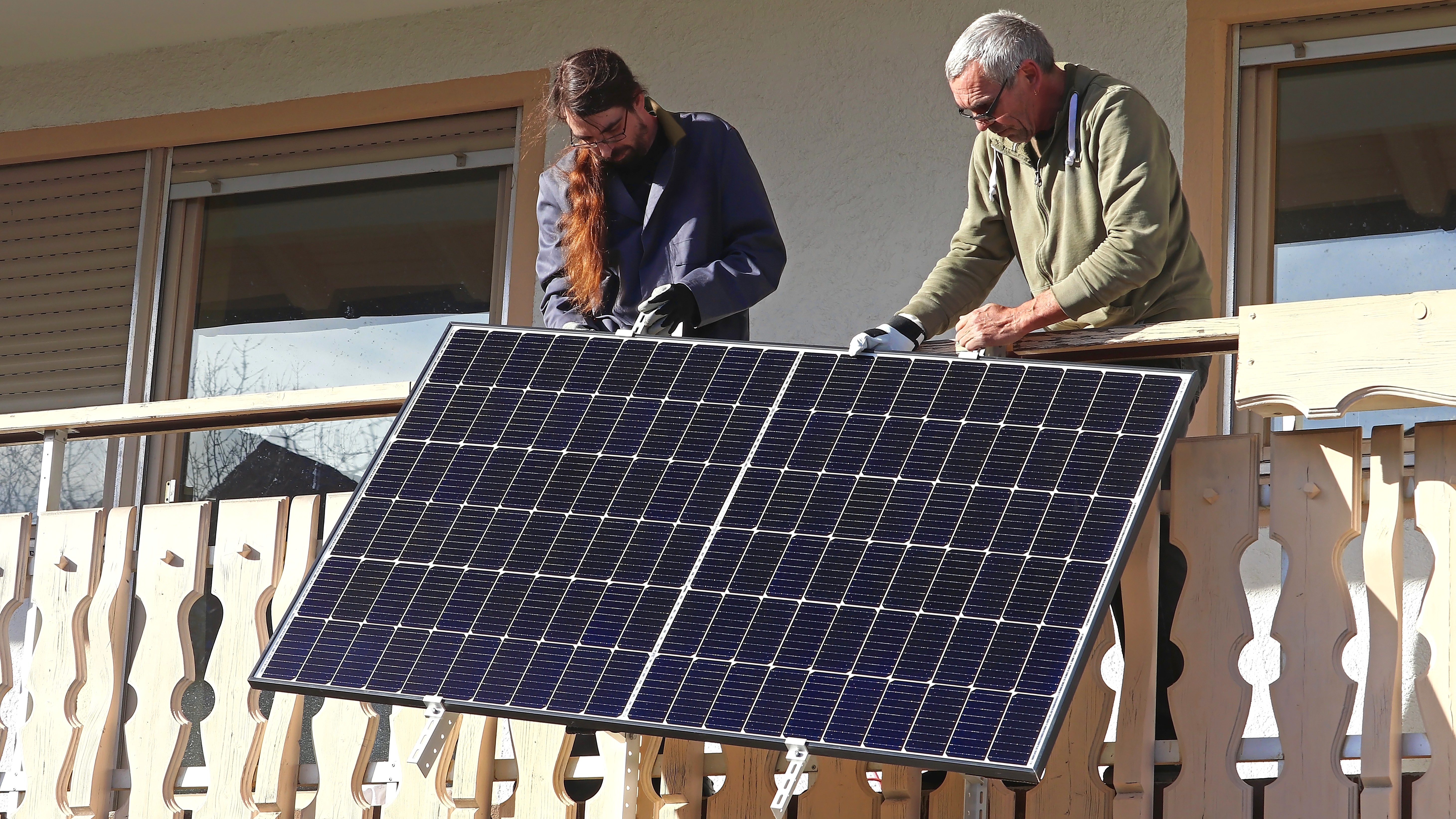 Two people installing solar panel on balcony