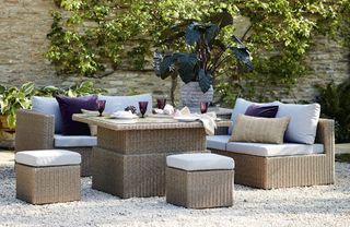 A rattan garden set with storage coffee table in a gravelled outside space