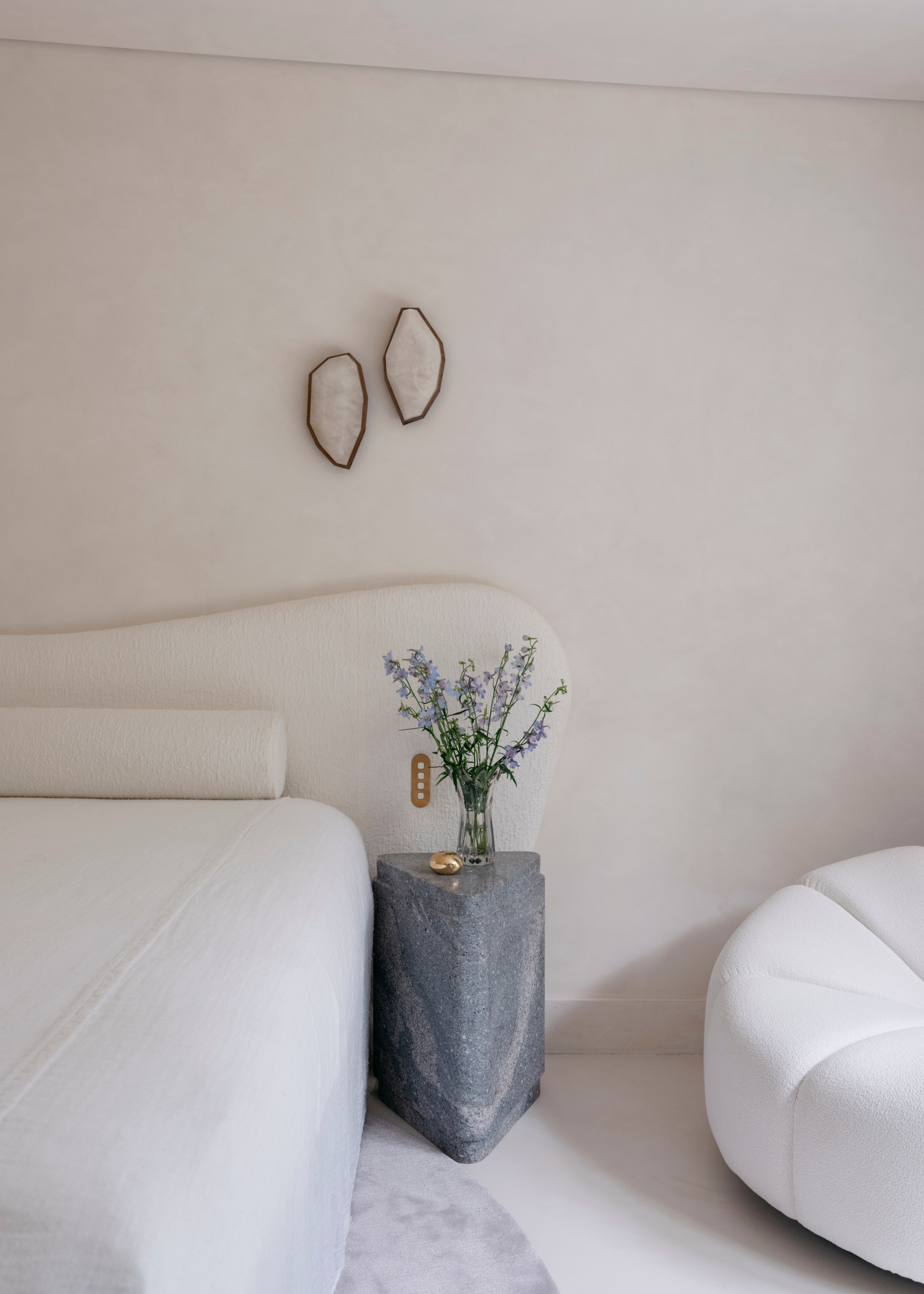 A neutral minimalist bedroom with a marble side table, geode wall decor and a sofa seater
