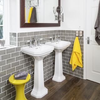 white bathroom grey tiled half wall double basin large wall mounted mirror dark wood flooring