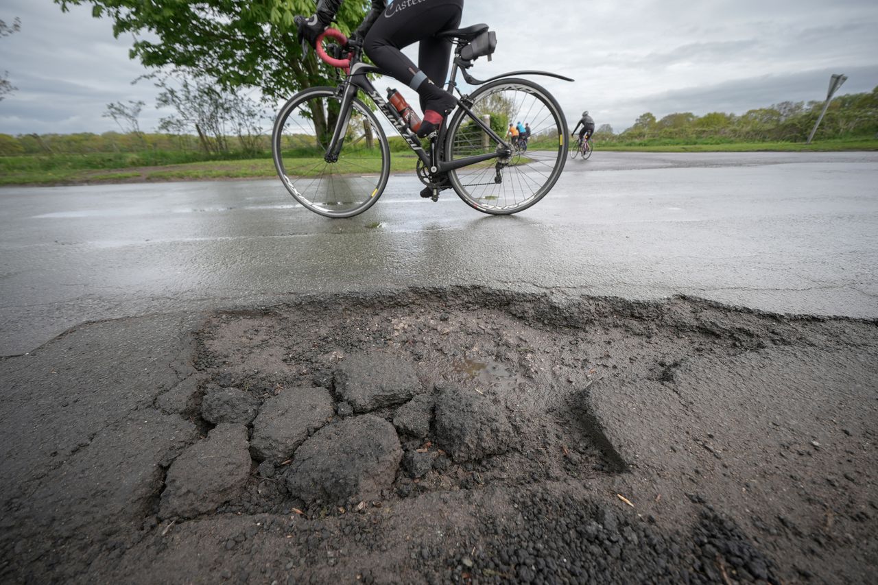 A man cycles near a pothole
