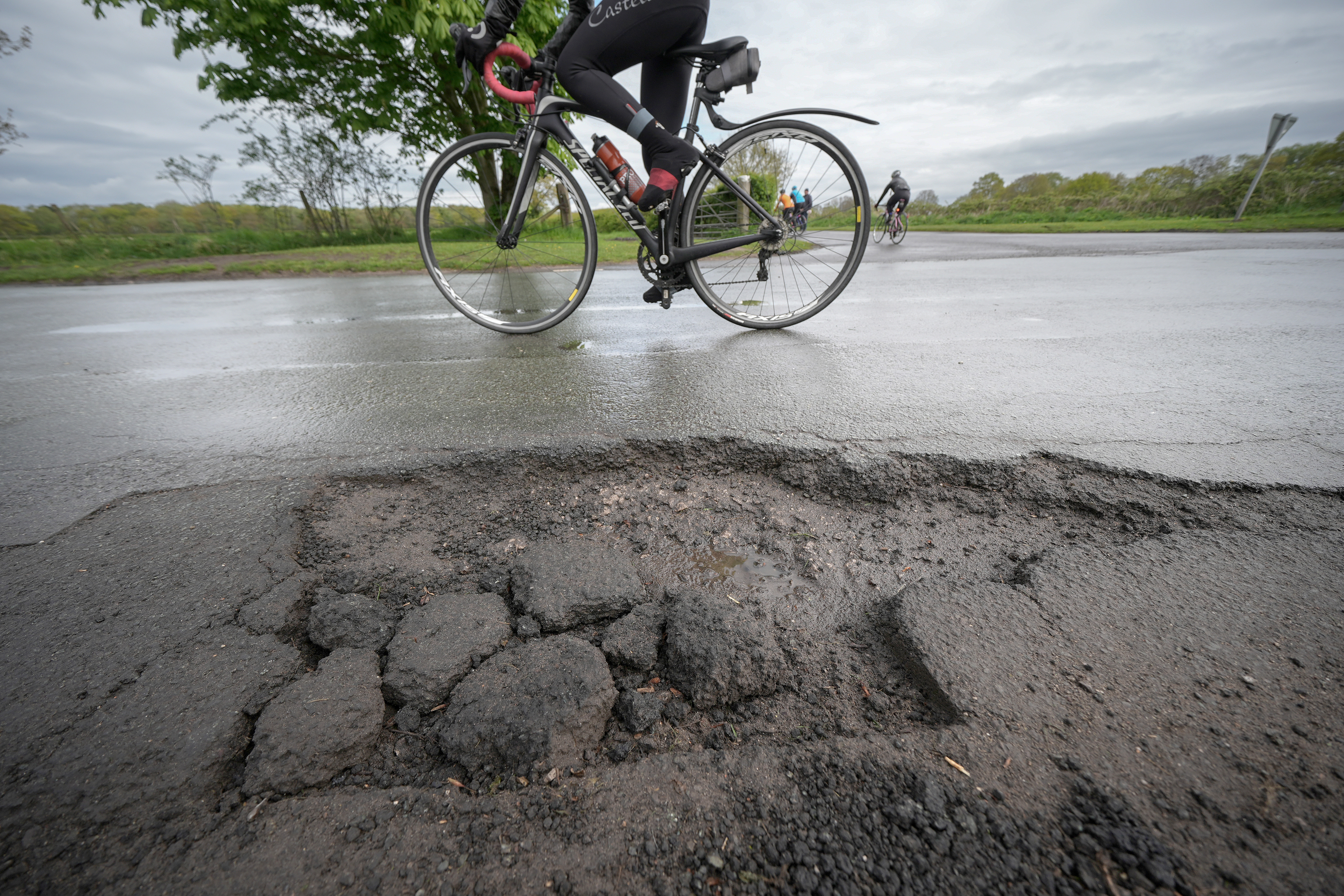 A man cycles near a pothole
