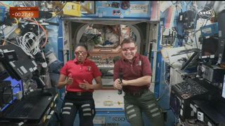 two smiling astronauts wear eclipse glasses on the international space station