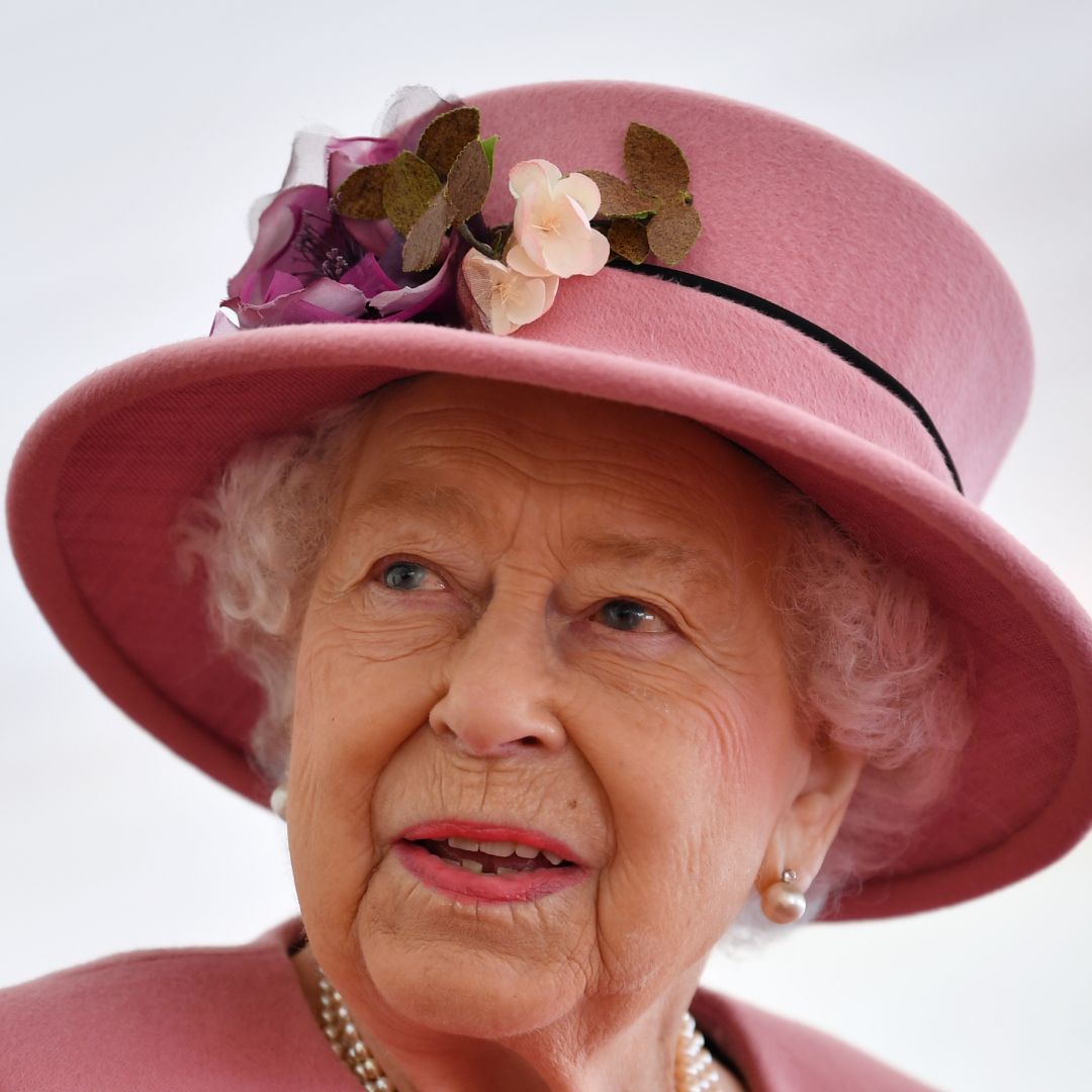 Queen Elizabeth wearing a pink hat and coat looking to the side