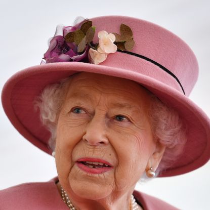 Queen Elizabeth wearing a pink hat and coat looking to the side