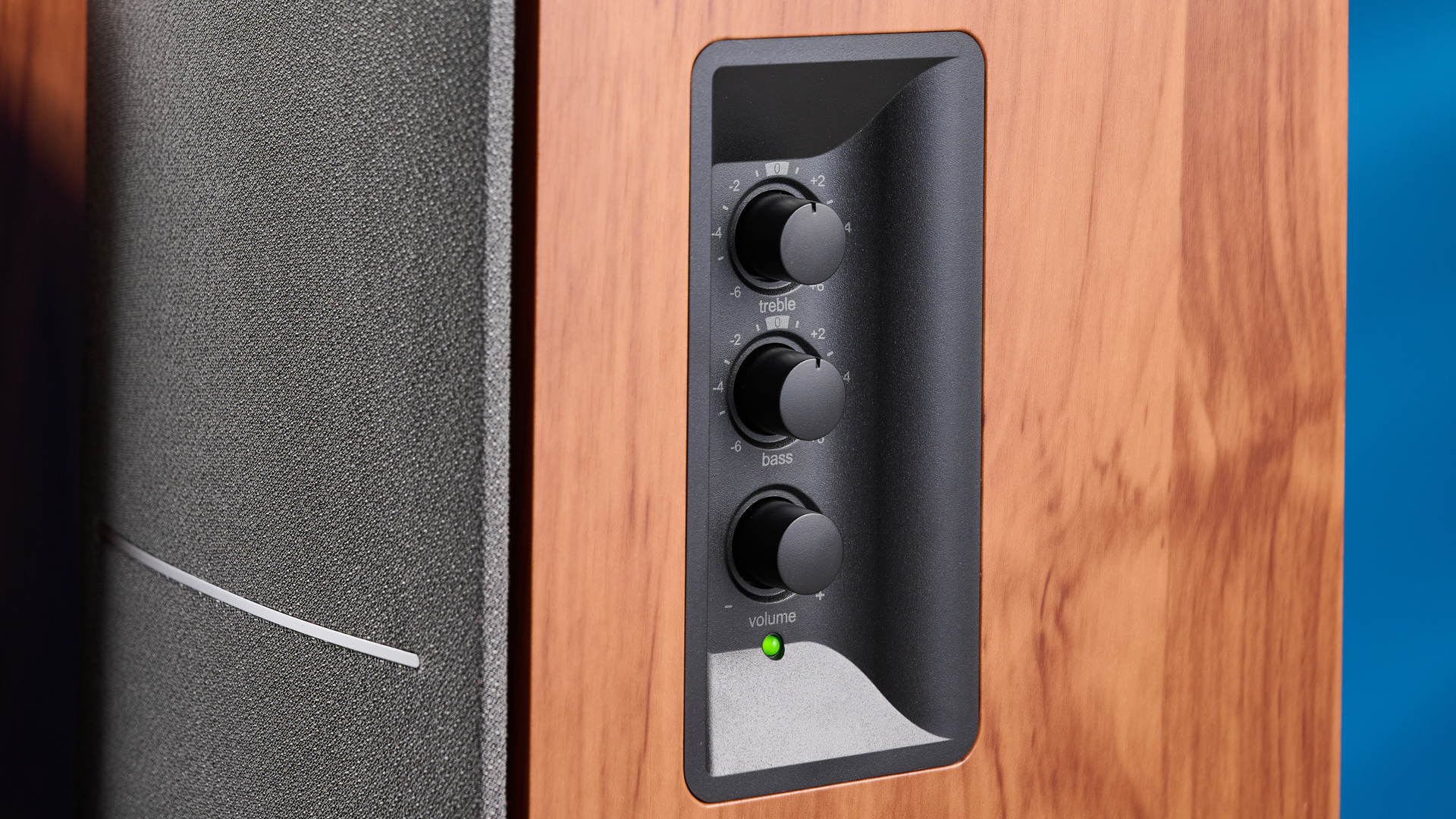 the edifier r1280t bookshelf speakers in wood brown photographed against the blue background, showing the volume adjustment dials, internal drivers and tweeters, RCA and aux inputs, and remote