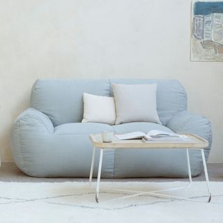 A light blue sofa with a desk in front of it