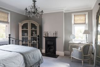 guest room with cast iron bed chandelier and armoire and upholstered chair