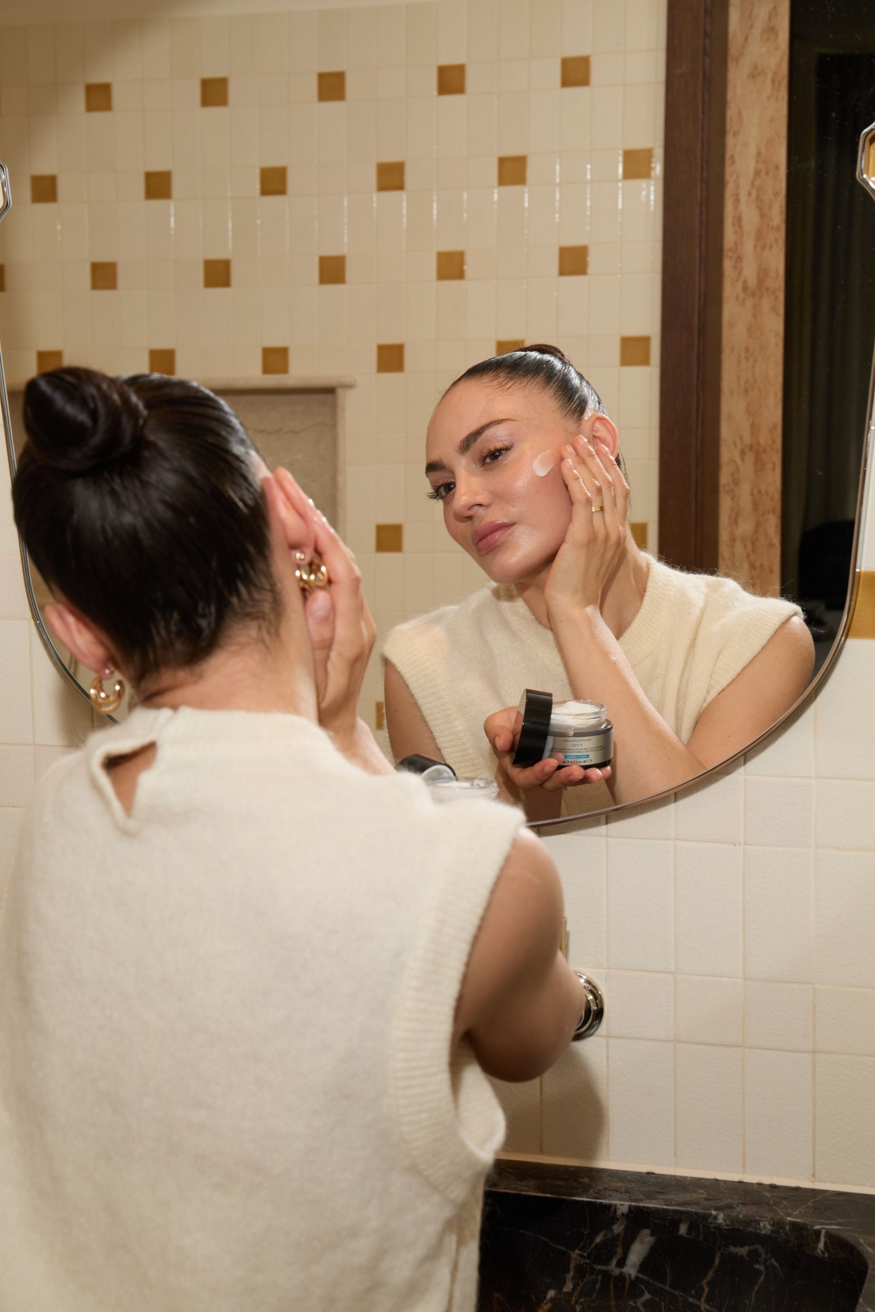 Eleanor Hartley applying a SkinCeuticals cream in the mirror