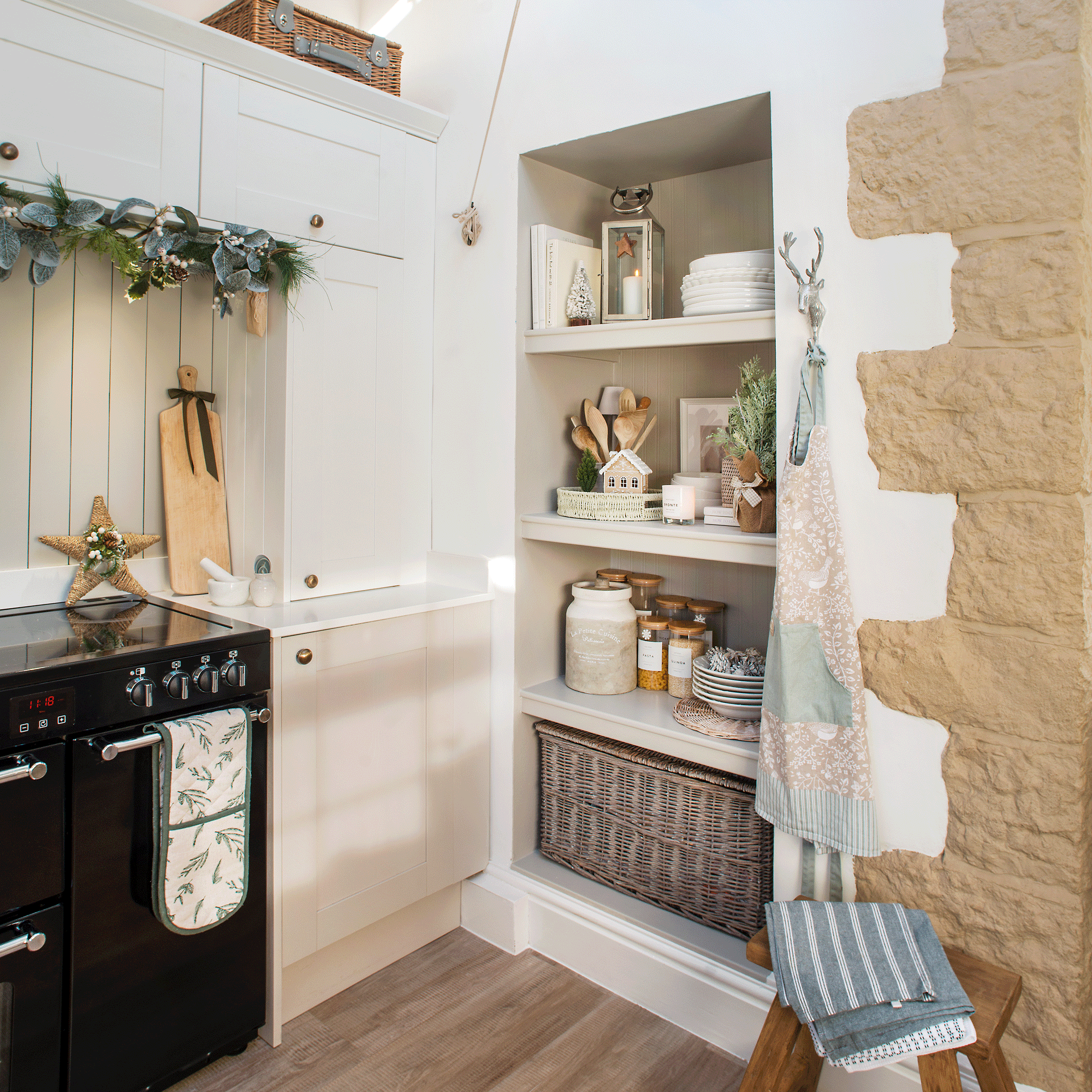 the corner of a neutral stone coloured kitchen with open shelving, a black range cooker and plenty of storage