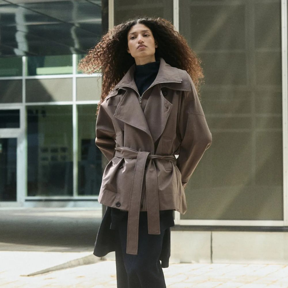 Woman wears trench coat, black top, black skirt
