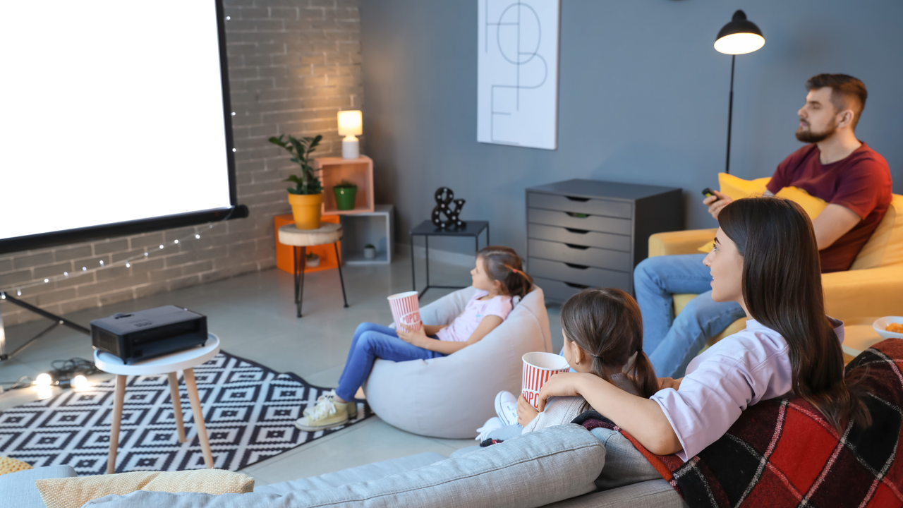 The best projector: Image depicts family sat on sofas around projector screen