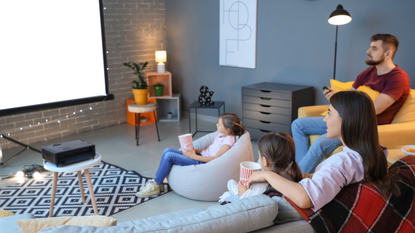 The best projector: Image depicts family sat on sofas around projector screen