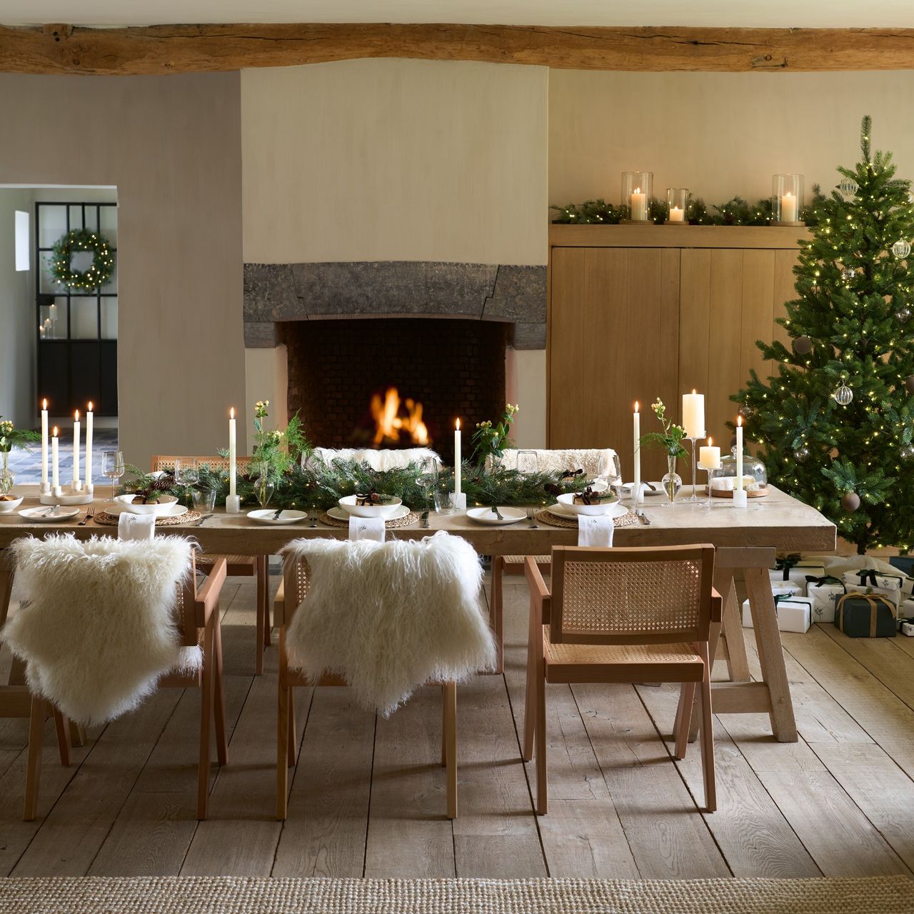 A large dining room with a long rectangular dining table decorated with The White Company&#039;s garland and tree in the corner
