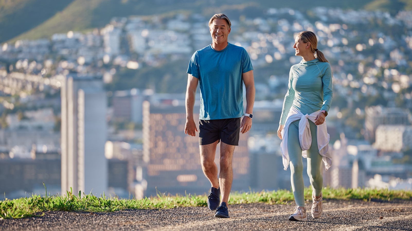 Fitness, morning and couple in city walking for exercise, cardio workout and training together. Marriage, happy and mature man and woman on hill for wellness, health and wellbeing in urban town