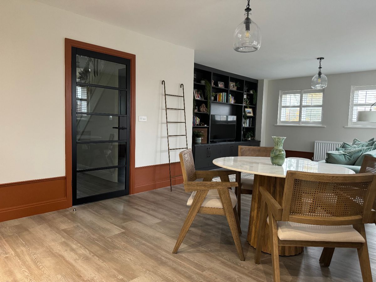 A dining room with tall burgundy skirting boards