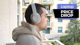Beats Studio Pro wireless headphones in sandstone colorway worn by man outside on a balcony 