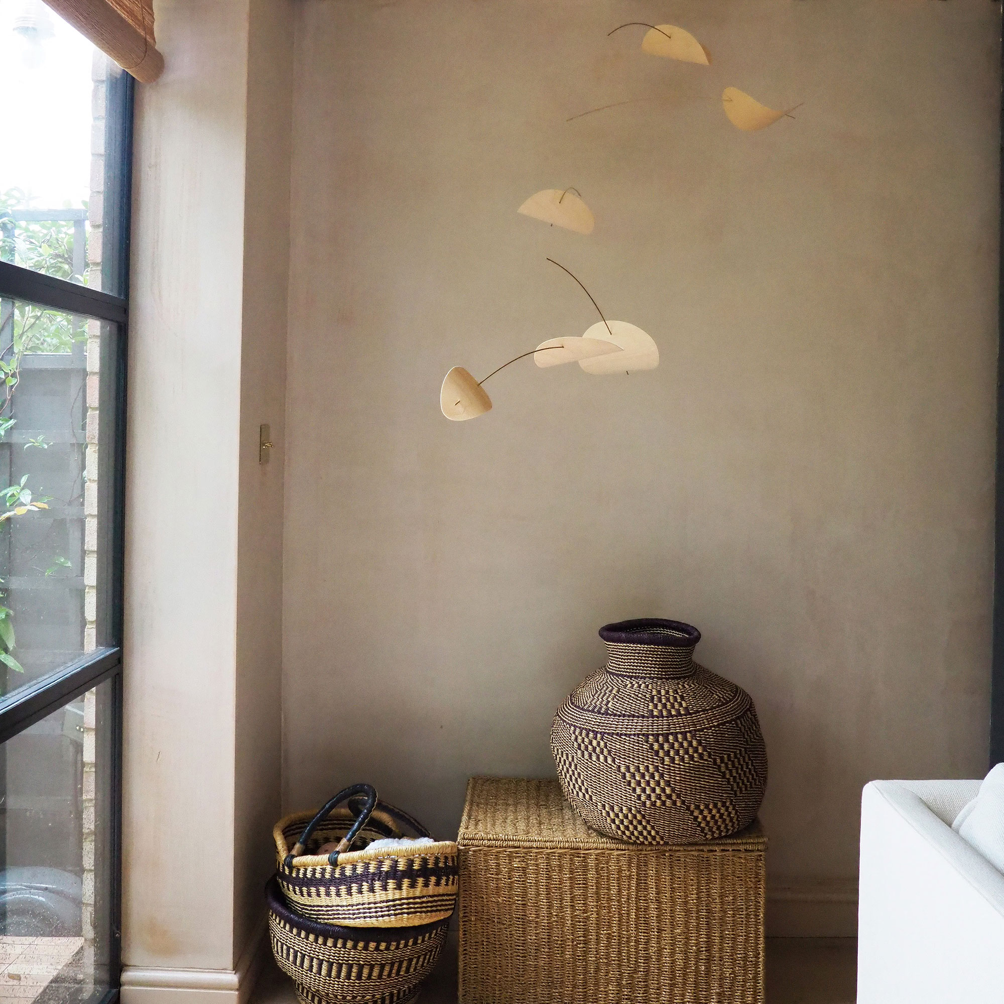 Neutral room with mobile pendant, woven box, vase and baskets