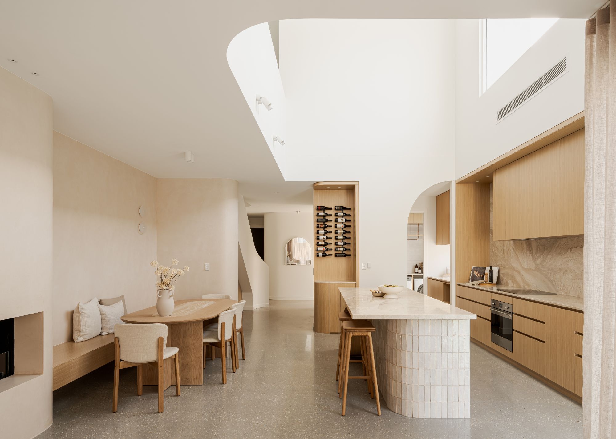 An open plan kitchen and dining, with wood tones and stone finishes