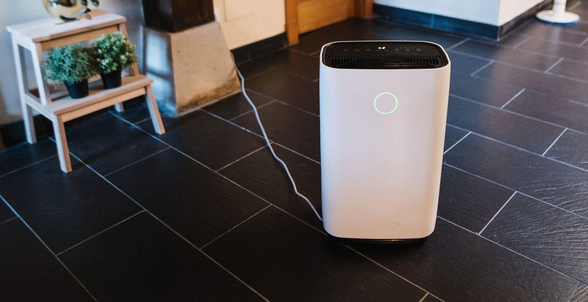 A black tiled floor with a dehumidifier plugged in to show the first step when looking how to clean a dehumidifier