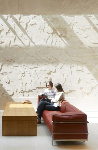 2 women sat on a sofa reading