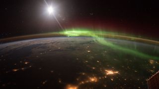 A photo of the Earth from the ISS with city lights and the aurora