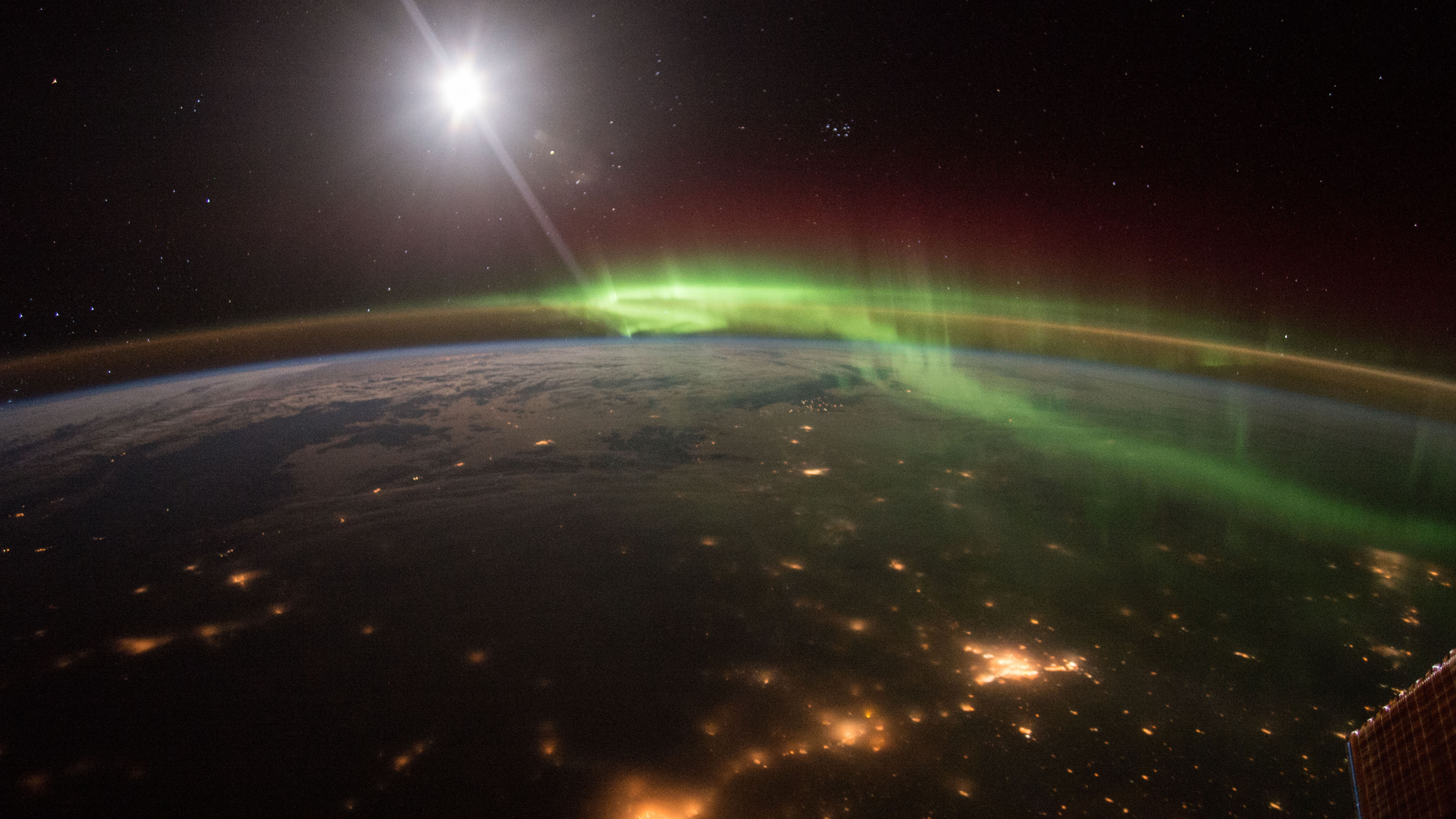 A photo of the Earth from the ISS with city lights and the aurora