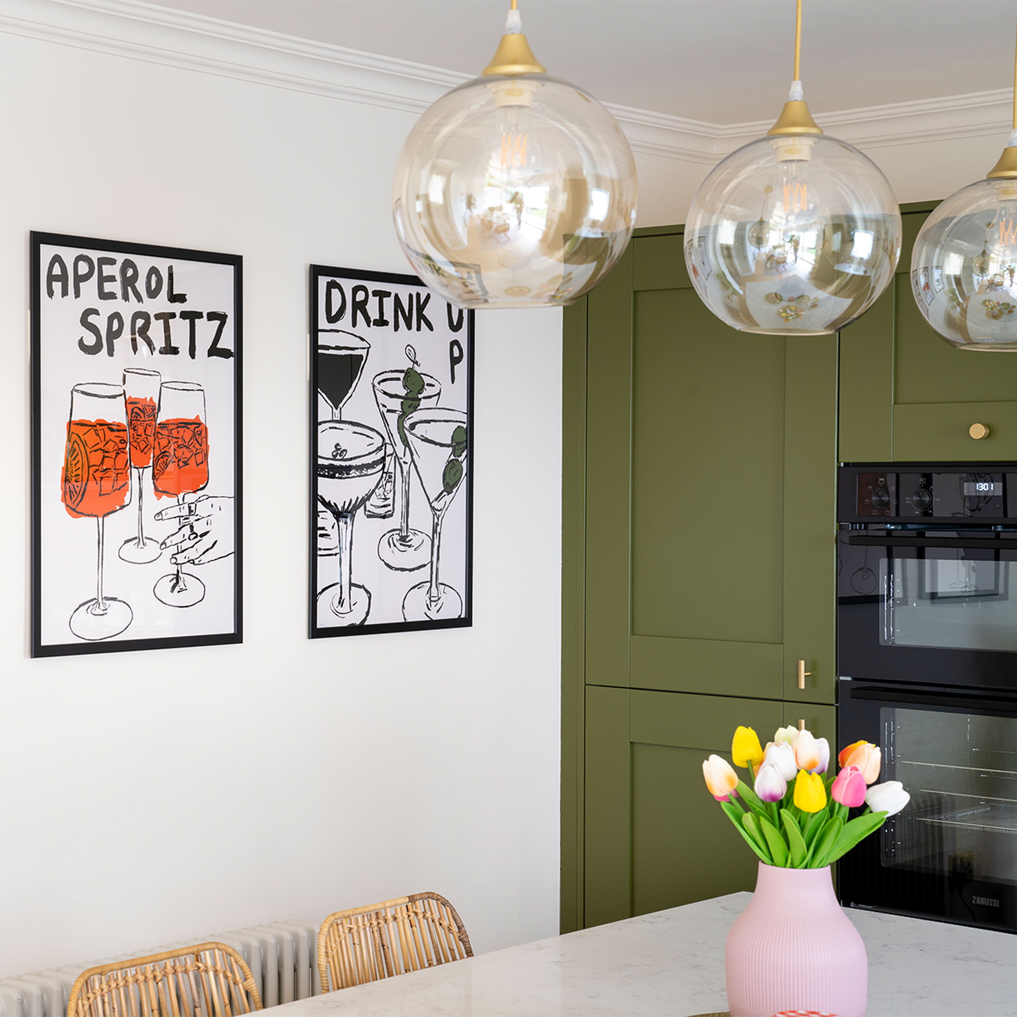 Green kitchen makeover with artwork and glass pendant lighs