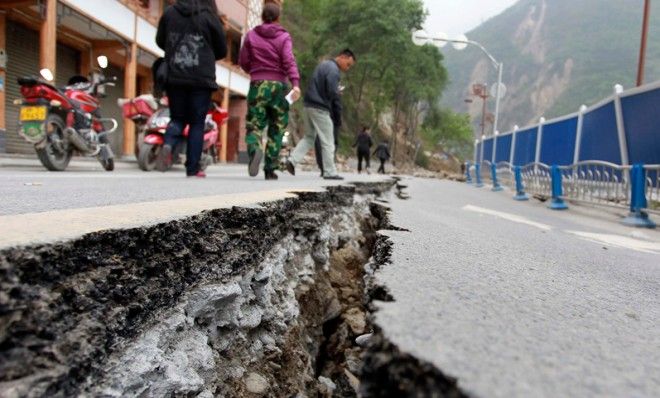 People walk next to a crack in the road after Saturday&amp;#039;s earthquake in Baoxing county, Sichuan province, April 21.