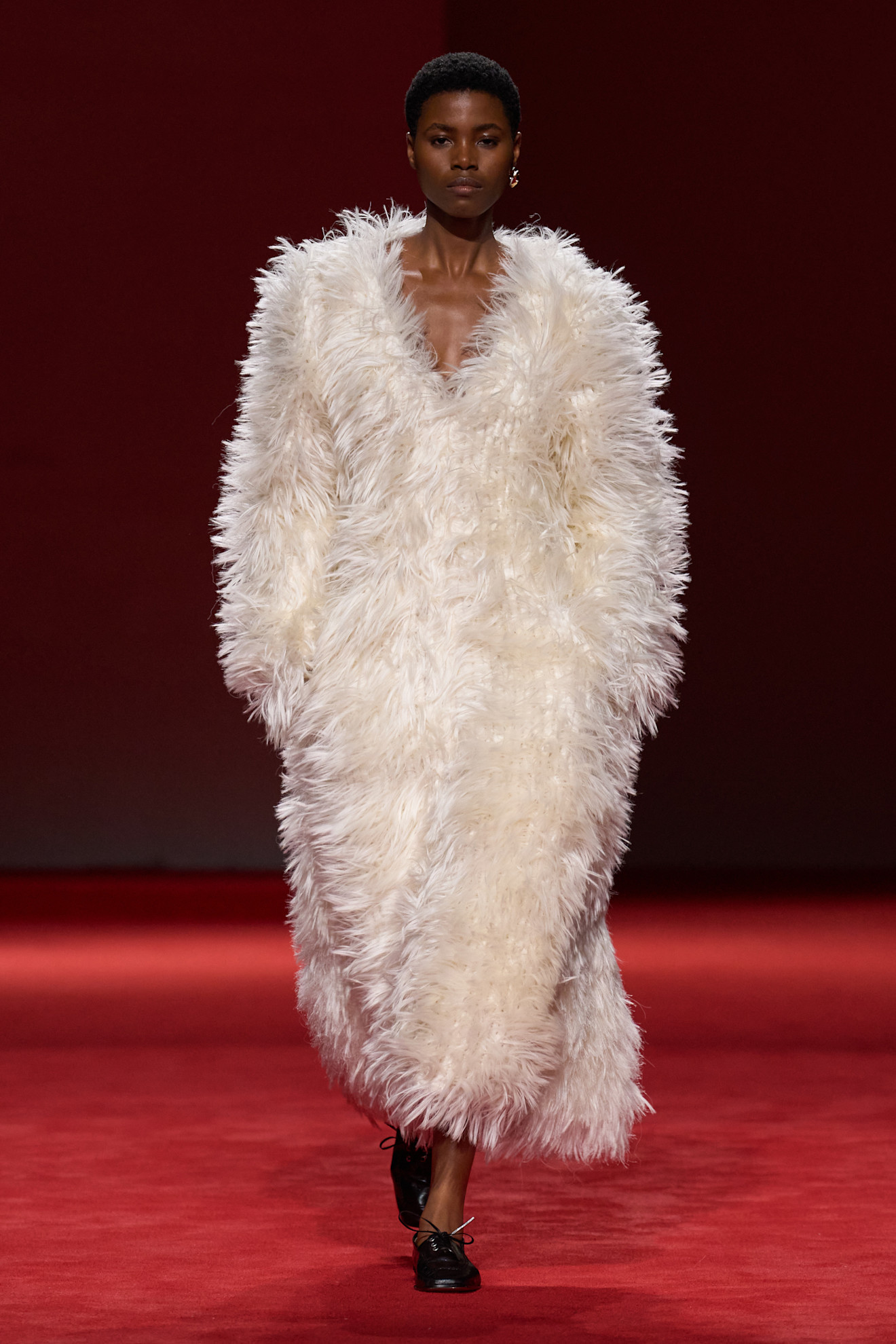 A model walking in the F/W 26 Bottega Veneta show during Milan Fashion Week wearing a cream textured V-neck dress.