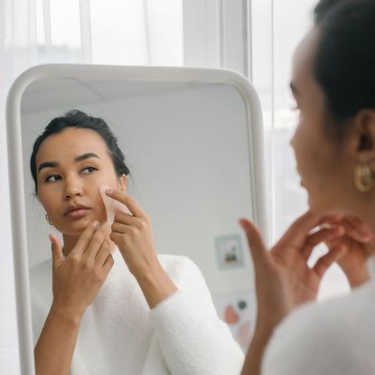 Gua Sha Routine- woman doing Gua Sha in the mirror