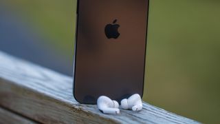 AirPods Pro 2 in front of iPhone 14 Pro Max on porch ledge