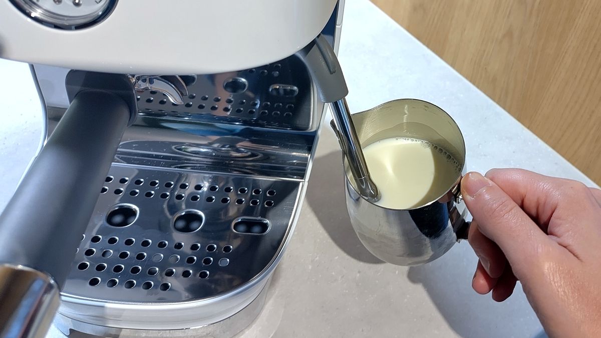 Person using Smeg ECF03 espresso machine steam wand to foam milk
