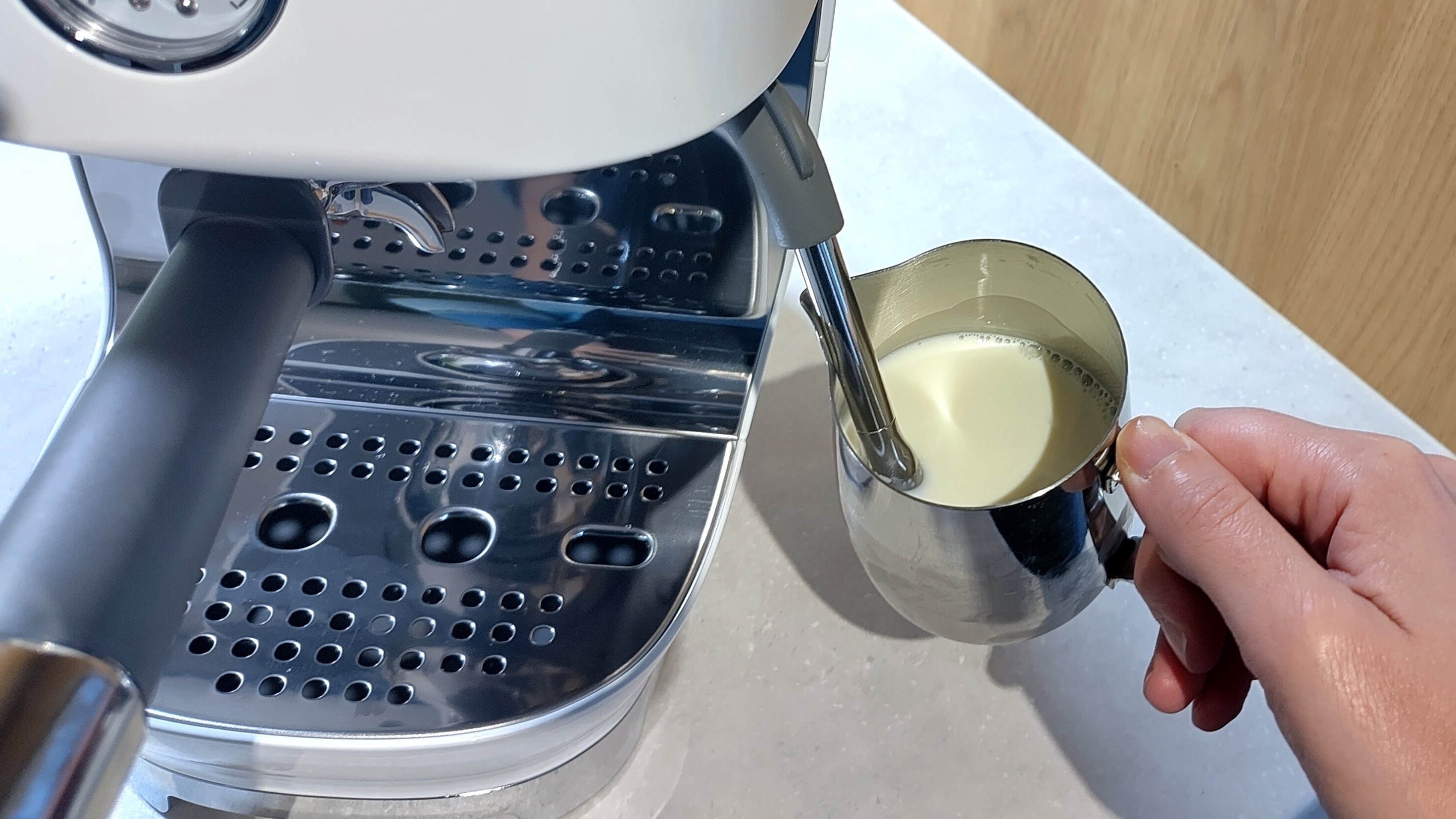 Person using Smeg ECF03 espresso machine steam wand to foam milk