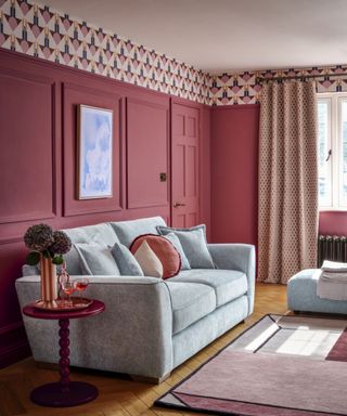 Pink living room with wallpaper border, blue sofa and pink lacquer side table