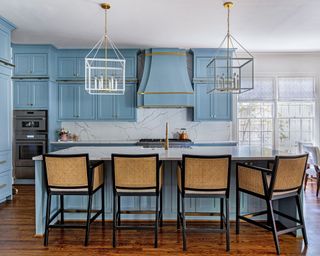 modern kitchen with mid-blue cabinets and kitchen island, rattan bar chairs and statement pendant lights