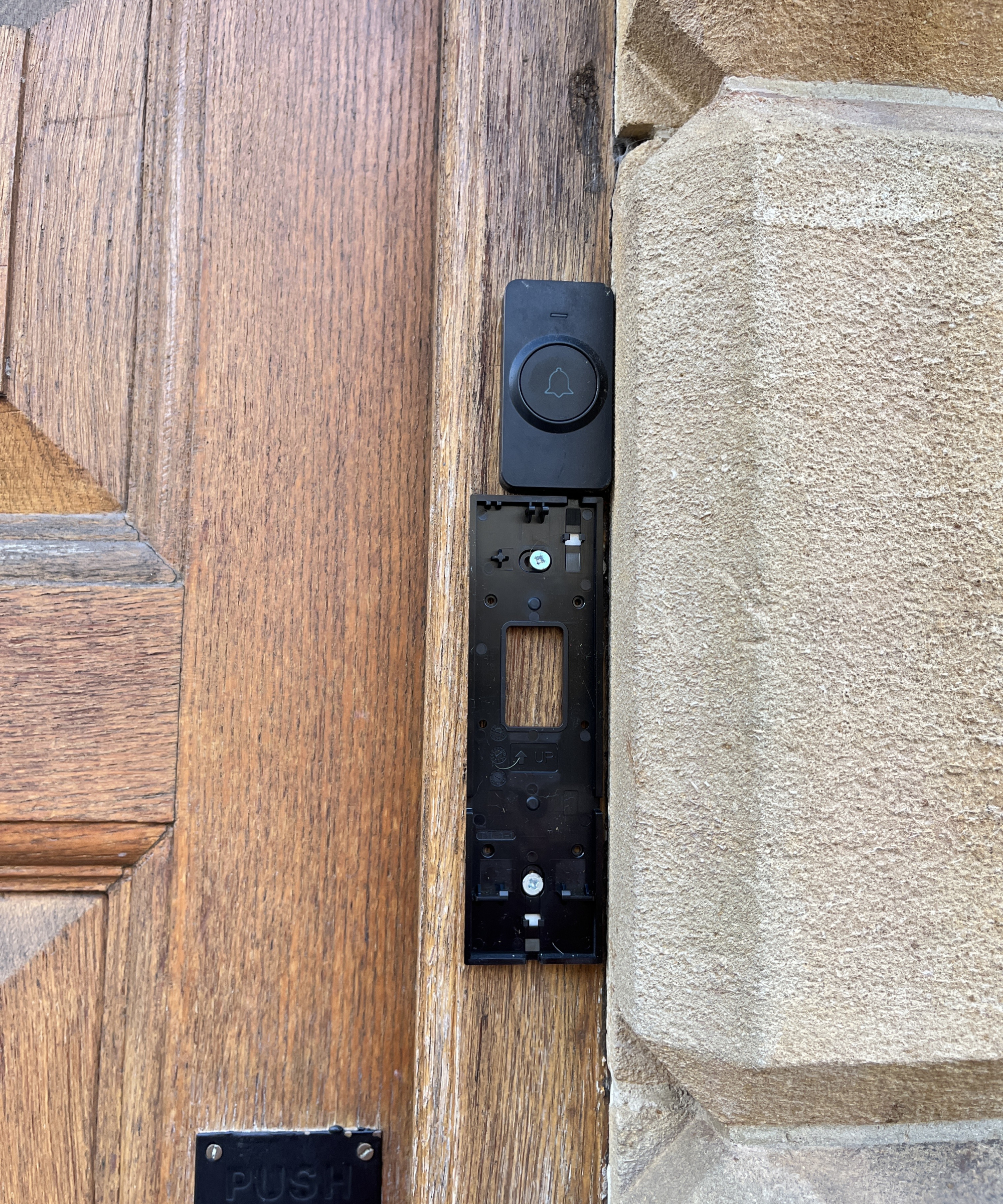 Ezviz video doorbell back panel being installed on wooden door frame