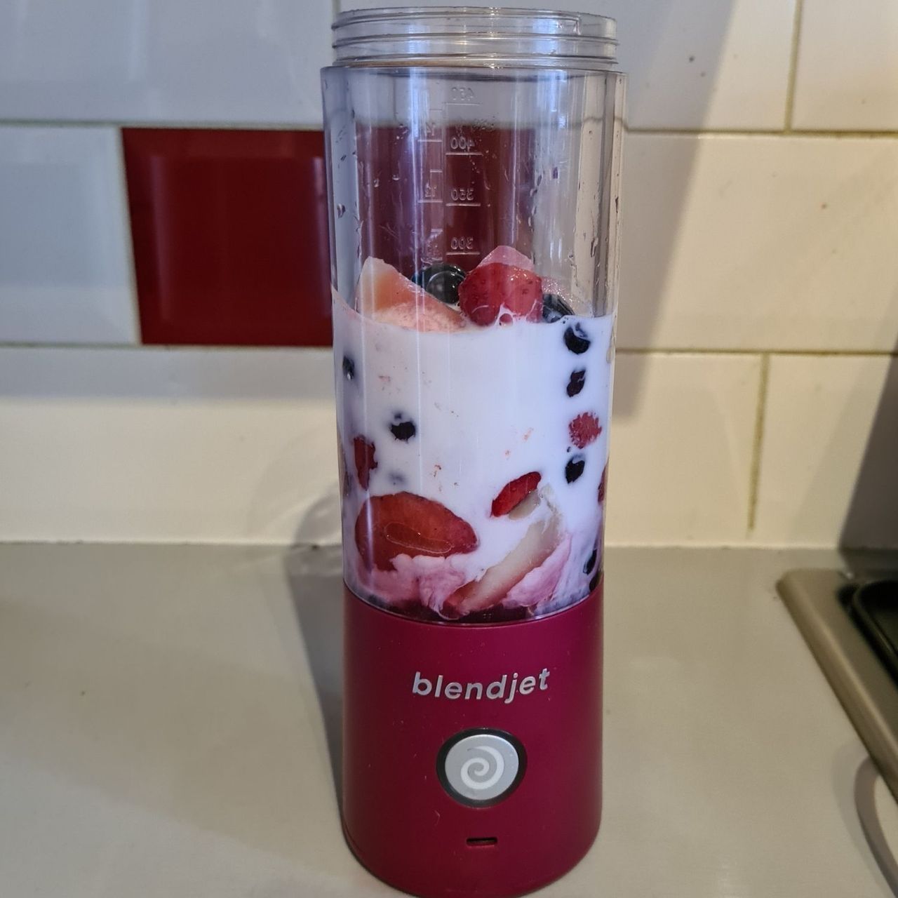 BlendJet 2 filled with milk and fresh berries to the half way line.