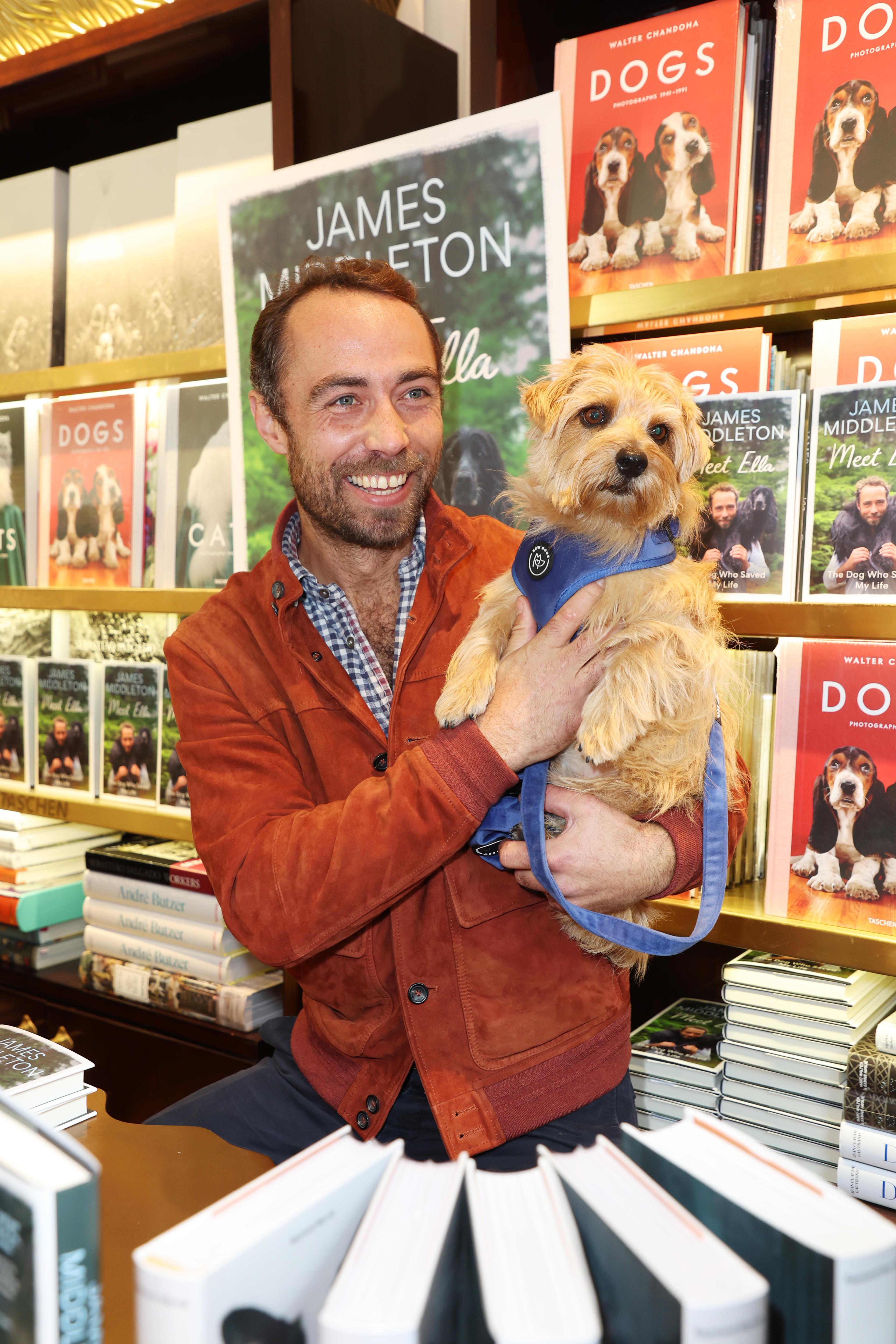 James Middleton holding a dog in front of a table full of his memoir and other dog books