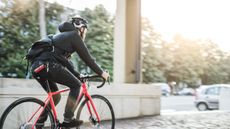 Bike messenger riding into a low sun, with a bike lock tucked away in his jeans pocket 